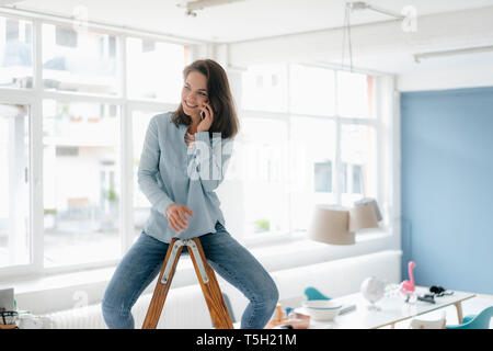 Bella donna seduta sulla scaletta, parlando al telefono Foto Stock