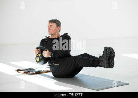 L uomo che sta facendo il suo regime fitness, bollitore facendo bell sit ups Foto Stock