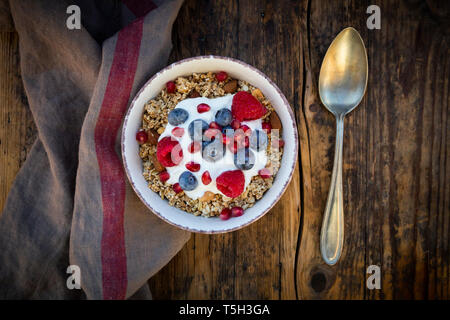 Ciotola di muesli con yogurt greco, schioccato la quinoa, Lamponi Mirtilli e i semi di melograno, dal di sopra Foto Stock