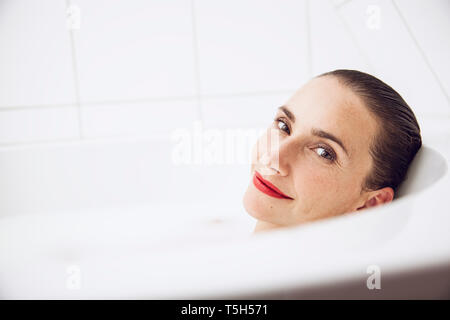 Bella donna rilassante in un bagno di latte Foto Stock