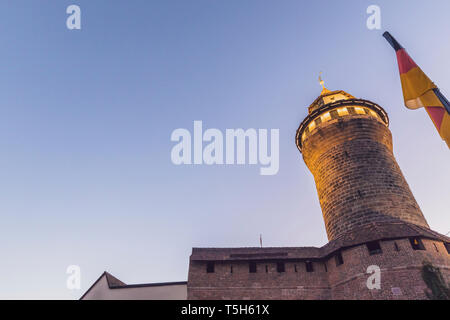 Germania, Norimberga, Castello di Norimberga, Sinwell Tower e la bandiera tedesca al blue ora a basso angolo di visione Foto Stock