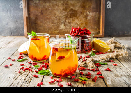 In casa goji tè caldo con la menta e le fette di limone, rustico in legno sfondo spazio di copia Foto Stock