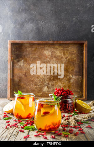 In casa goji tè caldo con la menta e le fette di limone, rustico in legno sfondo spazio di copia Foto Stock