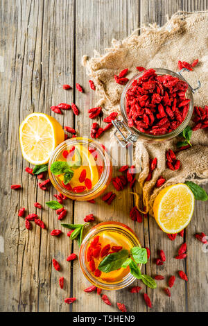 In casa goji tè caldo con la menta e le fette di limone, rustico in legno sfondo spazio di copia Foto Stock