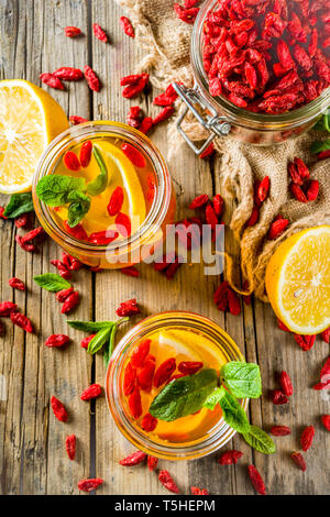 In casa goji tè caldo con la menta e le fette di limone, rustico in legno sfondo spazio di copia Foto Stock