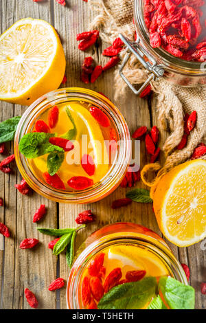 In casa goji tè caldo con la menta e le fette di limone, rustico in legno sfondo spazio di copia Foto Stock