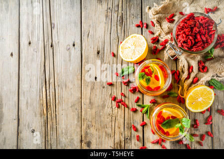 In casa goji tè caldo con la menta e le fette di limone, rustico in legno sfondo spazio di copia Foto Stock