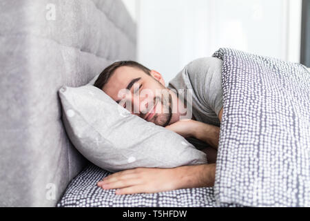 Uomo bello dormire nel letto di casa Foto Stock