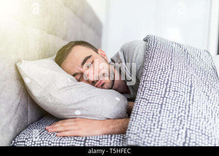 Uomo bello dormire nel letto di casa Foto Stock