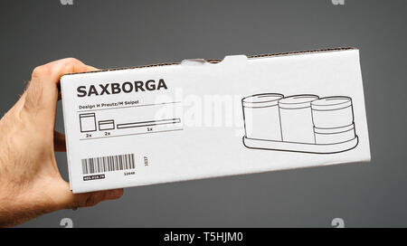 Parigi, Francia - Aprile 7, 2019: Man mano che tiene contro uno sfondo grigio scatola di cartone di vetro nuovo Ikea Saxborga set di quattro vasi con con sughero organico coperchio Foto Stock