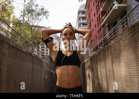 Giovane donna la sua legatura updo nella città Foto Stock