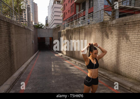 Giovane donna la sua legatura updo nella città Foto Stock