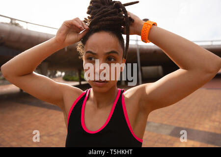 Giovane donna la sua legatura updo nella città Foto Stock