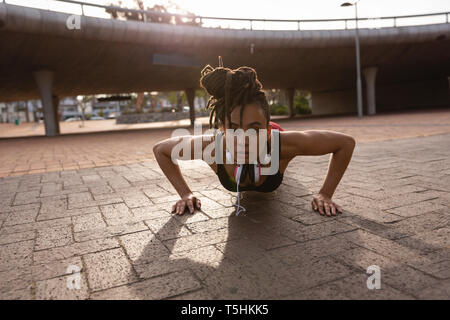 Giovane donna facendo push-up esercizio nella città Foto Stock