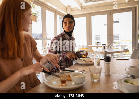 Amici di sesso femminile che interagiscono con ogni altro pur avendo prima colazione Foto Stock