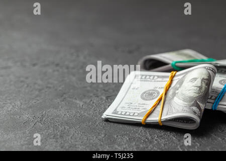 Pile di dollari di cassa legato con ufficio colorate bande su sfondo scuro. Concetto di risparmio o di corrompere. Copia spazio per il testo Foto Stock