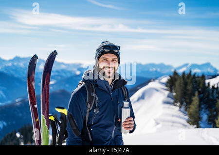 In Germania, in Baviera, Brauneck, ritratto di uomo sorridente in un tour di sci in inverno in montagna avente una pausa Foto Stock