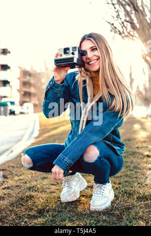 Ritratto di sorridente giovane donna utilizzando instant fotocamera Foto Stock