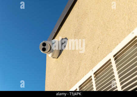 Videocamera di sicurezza montato su una parete, puntata direttamente al visualizzatore Foto Stock