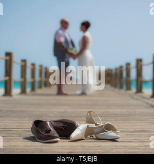 Coppia sposata sul giorno di nozze camminando romanticamente esterno sul molo in legno con un paio di scarpe in primo piano Foto Stock