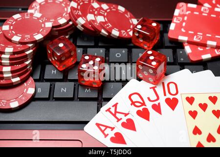 Casino chips, schede e dadi impilare su un computer portatile Foto Stock