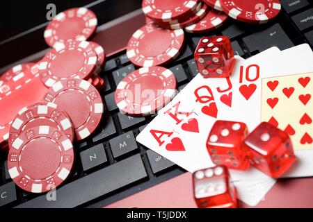 Casino chips, schede e dadi impilare su un computer portatile Foto Stock