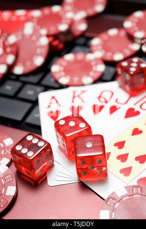Casino chips, schede e dadi impilare su un computer portatile Foto Stock
