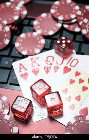 Casino chips, schede e dadi impilare su un computer portatile Foto Stock