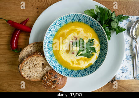 Ciotola di sana zuppa di zucca con pane, peperoncino e prezzemolo Foto Stock