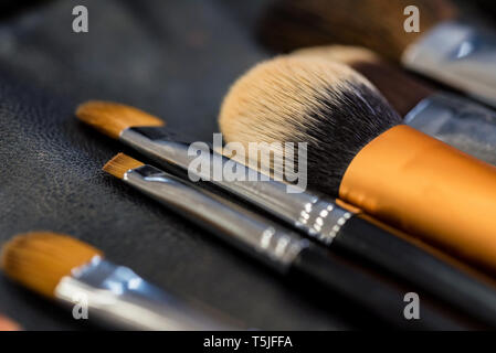 Set di pennelli per il trucco giacente sulla superficie scura vicino Foto Stock