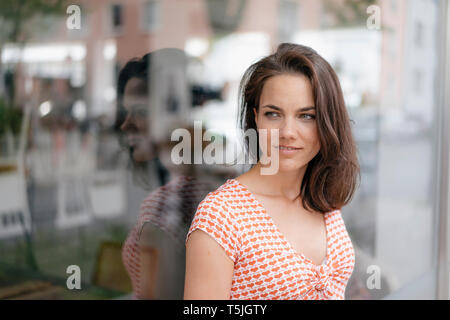 Ritratto di una donna graziosa, in piedi nella parte anteriore della finestra di visualizzazione Foto Stock
