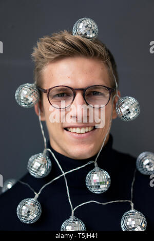 Ritratto di giovane sorridente uomo che indossa la sfera dello specchio le luci fairy Foto Stock