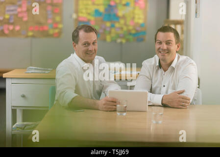 Ritratto di due imprenditori sorridente con la compressa in office Foto Stock