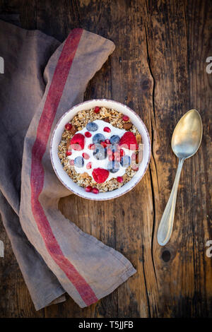 Ciotola di muesli con yogurt greco, schioccato la quinoa, Lamponi Mirtilli e i semi di melograno, dal di sopra Foto Stock