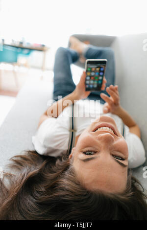Donna sdraiata sul lettino, utilizza lo smartphone Foto Stock