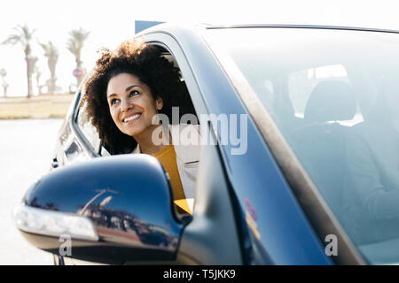 Donna felice guardando fuori della finestra auto Foto Stock