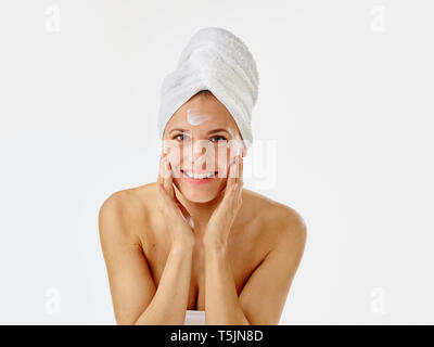 Giovane donna l'applicazione di crema per il viso sul suo viso Foto Stock
