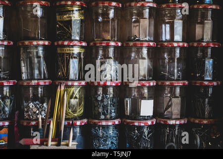 Close up della pila di vasi di marmellata contenente selezione di unghie e viti. Foto Stock