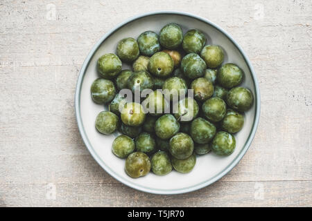 Angolo alto close up greengages fresca in bianco ciotola. Foto Stock