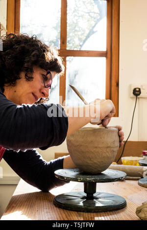 Donna seduta nel suo laboratorio di ceramica, lavorando sul vaso di creta. Foto Stock