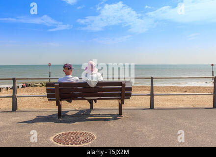 Coppia di anziani seduti su una panchina che guarda al mare presso la spiaggia di Avon, Mudeford, Christchurch, Dorset Regno Unito Foto Stock