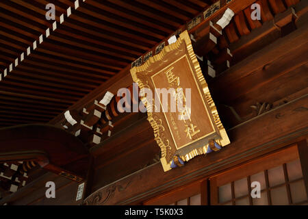 Una placca di oro segno scritto "Santuario aginu' appeso sopra l'ingresso principale dell'edificio al santuario Maginu, Kawasaki, Giappone. Foto Stock