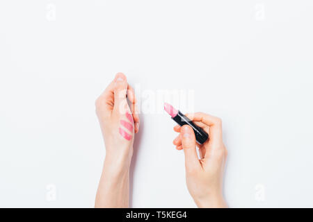 Donna con le mani in mano applicare il campione di prova di rossetto rosa sul retro del palmare Palm, vista dall'alto. Appartamento laici composizione minima femmina cerca colore della cosmetica decorativa sul Foto Stock