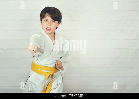 Bambino in posizione di karate contro Sfondo mattone Foto Stock