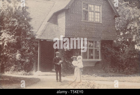 L'annata 1905 Pangbourne, Berkshire Cartolina fotografica che mostra una storica British Casa indipendente. Edwardian giovane e il loro bambino si fermò nel giardino anteriore. Foto Stock