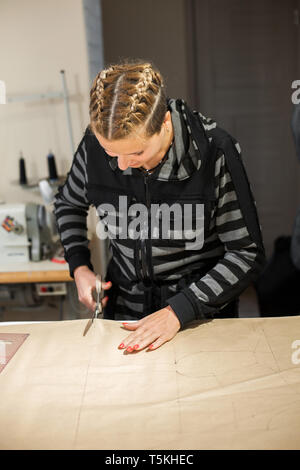 Donna bionda sarta tagli dal craft modello di carta per la realizzazione di abiti. Foto Stock