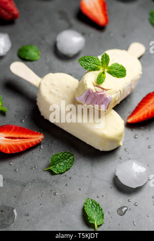 Gelato alla fragola stick ricoperto di cioccolato bianco Foto Stock