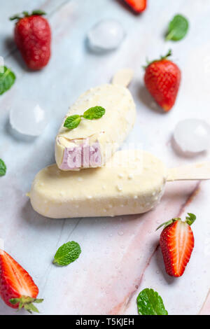 Fragola gelati su bastoncini ricoperti di cioccolato bianco Foto Stock