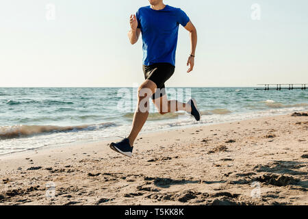 Gli uomini atleta runner in esecuzione sul mare spiaggia sabbiosa Foto Stock