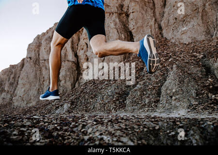 Gambe uomo runner in esecuzione sulla montagna sentiero di pietre Foto Stock